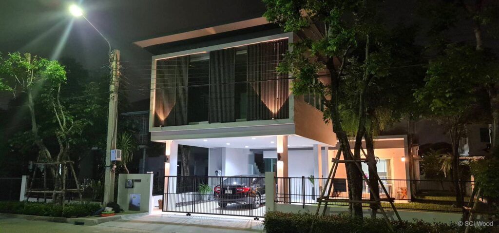 บ้านสองชั้นเวลากลางคืนพร้อมแผงระแนงแนวตั้งและไฟส่องด้านหน้า