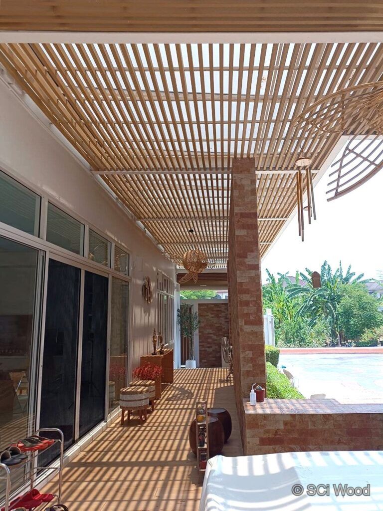 ทางเดินข้างบ้านใต้หลังคาระแนงโปร่ง มีเงาเส้นทอดบนพื้น