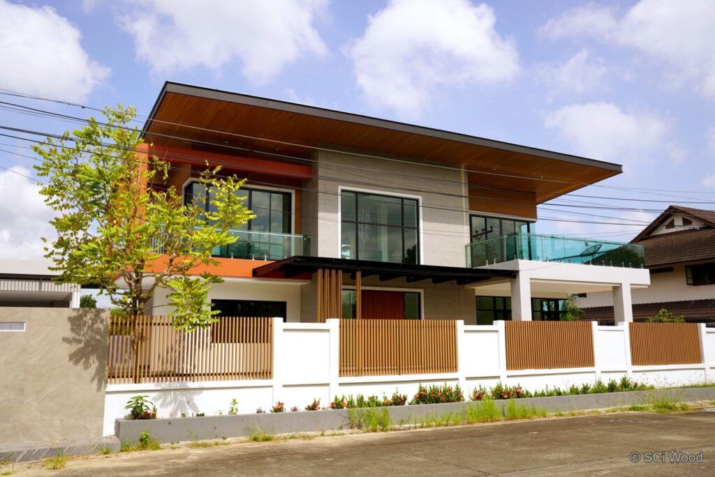 บ้านสองชั้นสีขาวเทาพร้อมรั้วและซี่ระแนงโทนน้ำตาลด้านหน้า